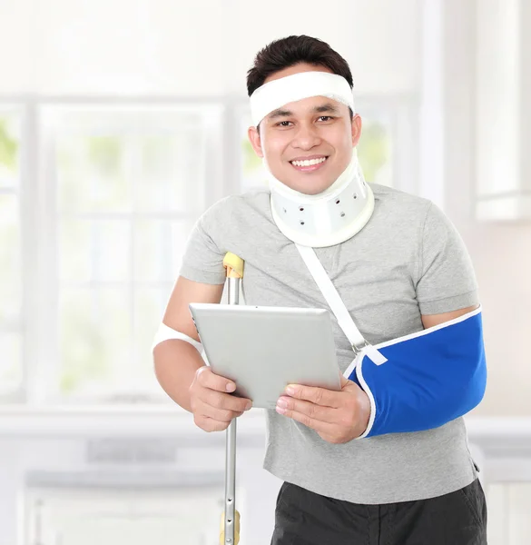 Injured young man holding a tablet — Stock Photo, Image