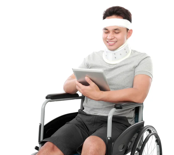 Blessé jeune homme en fauteuil roulant jouer sur une tablette — Photo