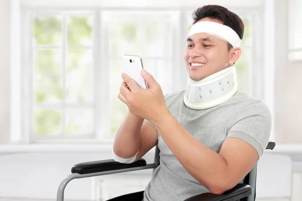 Zranil mladý muž ve hře vozíku na jeho smartphione — Stock fotografie