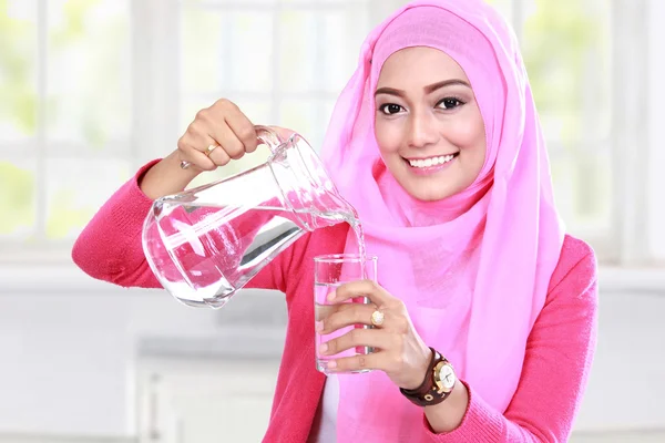 Giovane donna musulmana versando acqua in un bicchiere — Foto Stock