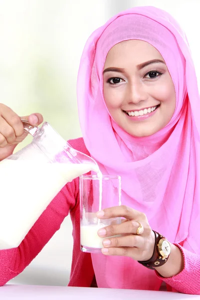 グラスに牛乳を注いで若いイスラム教徒の女性 — ストック写真