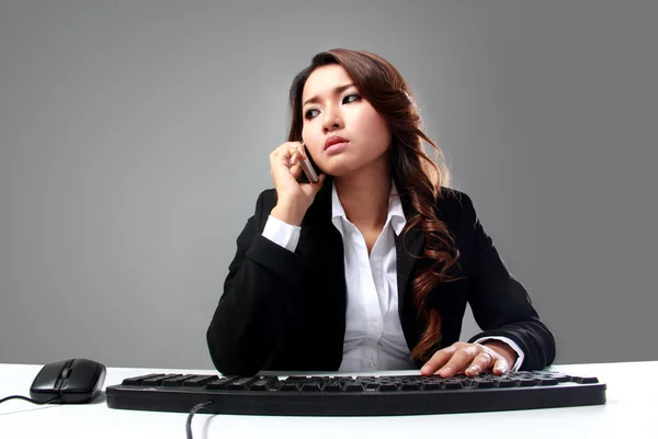 Jonge Aziatische zakenvrouw spreken op de telefoon tijdens het typen — Stockfoto