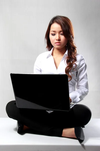 Mladá podnikatelka pracovat s notebookem, zatímco sedí na f — Stock fotografie