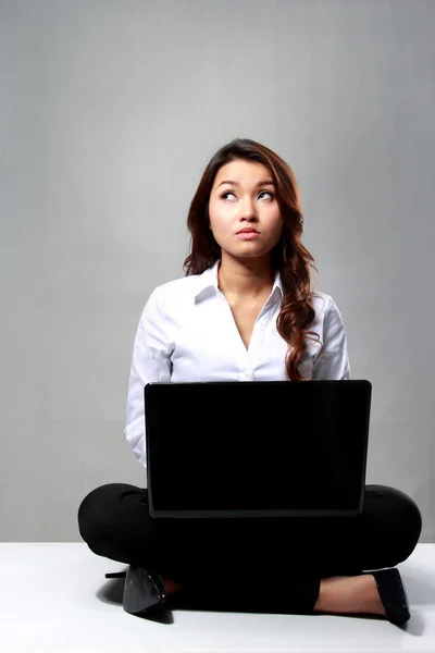 Молодая деловая женщина думает во время работы с ноутбуком — стоковое фото