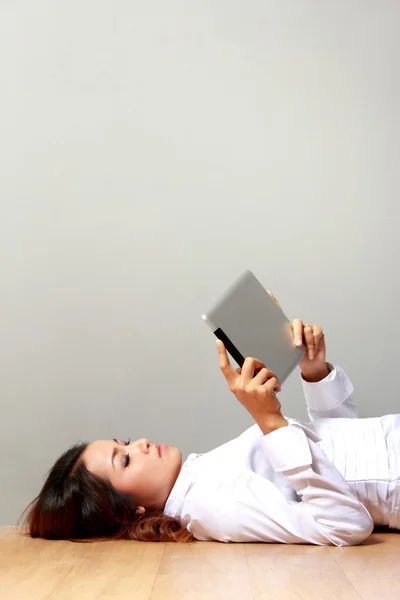 Young businesswoman  laying on the floor with a tablet — Stock Photo, Image