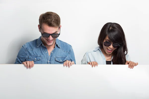 Glückliches junges Multikulti-Paar mit weißer Plakatwand — Stockfoto