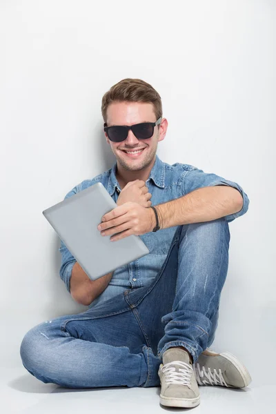 Молодий чоловік сидить на підлозі посміхається ізольовано — стокове фото