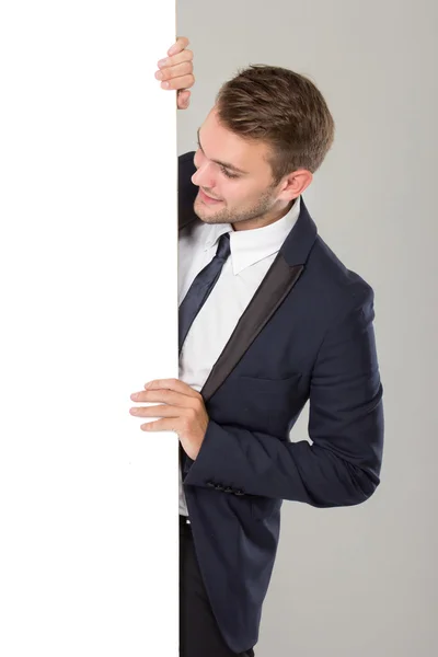 Joven hombre de negocios en traje negro mirando pizarra blanca en blanco —  Fotos de Stock
