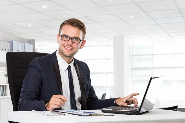 Jovem empresário posando na frente do laptop — Fotografia de Stock