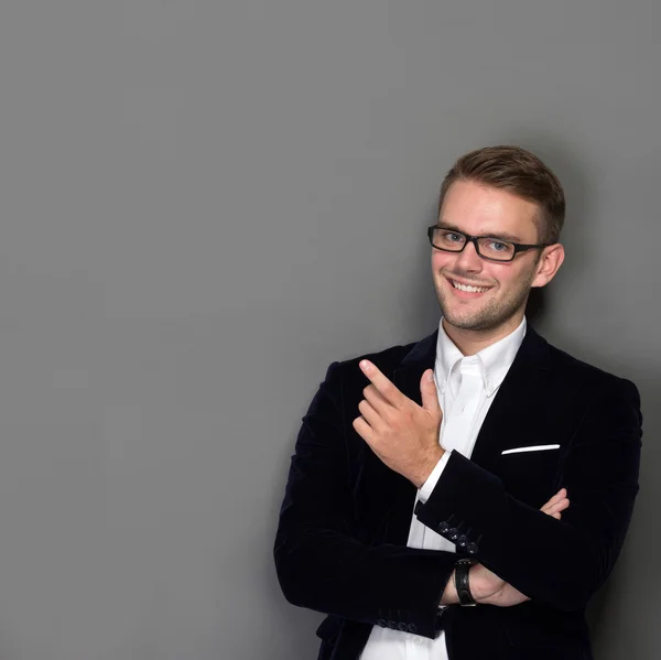 Joven hombre de negocios apoyado en la pared en traje de trabajo, sonriendo — Foto de Stock