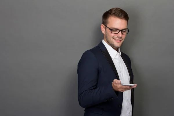 Jovem empresário com um celular na mão — Fotografia de Stock