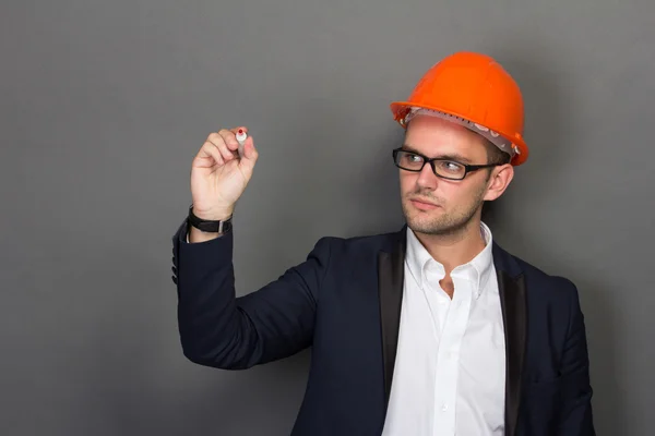 Un jeune homme d'affaires porte un casque de sécurité, écrivant — Photo