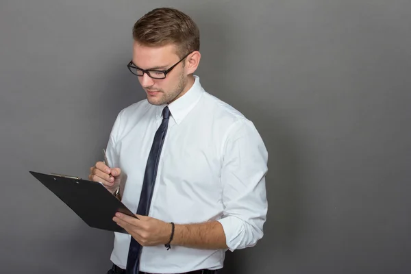 Young businessman writing on a clipboard — Stock Photo, Image