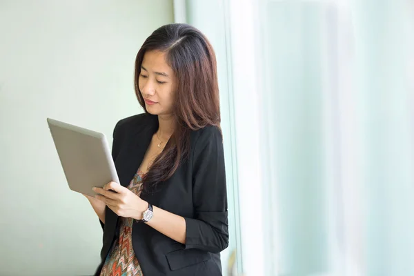 Jonge zakenvrouw permanent terwijl blik op een tablet pc — Stockfoto