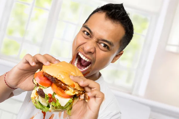 Молода людина є велике бажання з'їсти гамбургер — стокове фото
