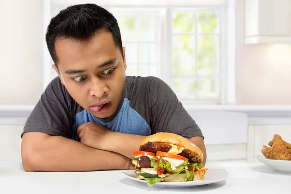 Ung man har en stor önskan att äta en hamburgare — Stockfoto