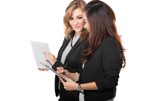 Twee jonge zakenvrouw bespreken met een klembord, geïsoleerd — Stockfoto