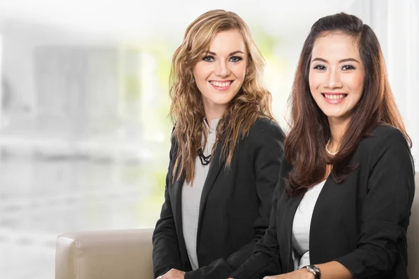 Two young businesswoman sitting next to each other, smile — Stock Photo, Image