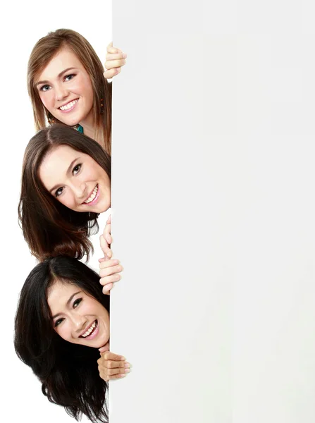 Trois filles voient à travers le mur blanc — Photo