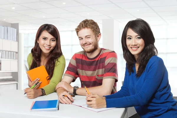 Trzy uśmiechający się studentów studiujących razem — Zdjęcie stockowe