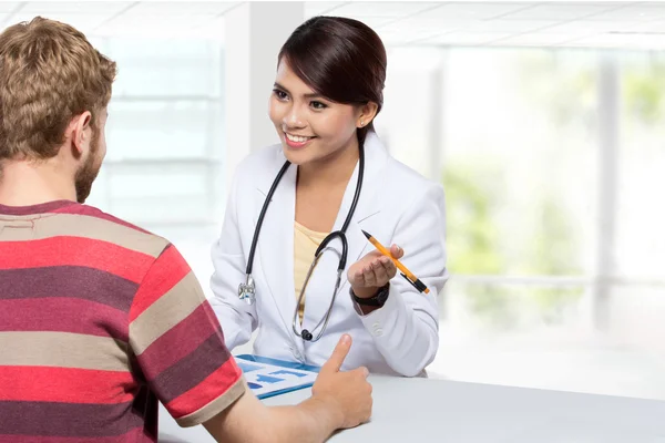 Médico sorrindo dando uma consulta a um paciente em seu médico — Fotografia de Stock