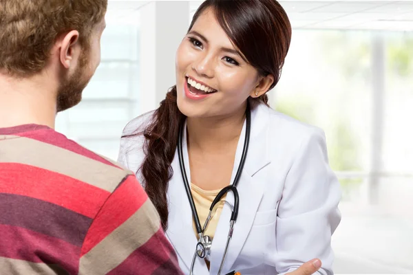 Médico sonriente dando una consulta a un paciente en su médico —  Fotos de Stock