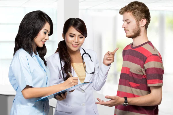 Médico sonriente dando una receta a un paciente asistido por — Foto de Stock