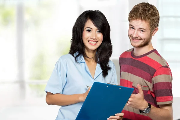 Een verpleegster uit te leggen aan een mannelijke patiënt — Stockfoto