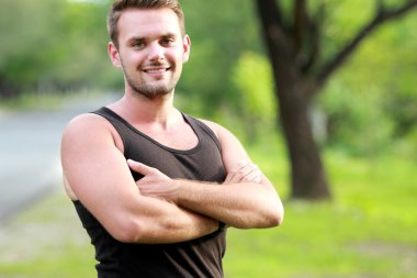 Sportif delikanlı gülümseyen ve poz katlanmış kolu