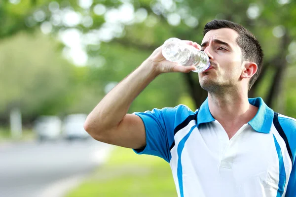 Sportif coureur mâle boire de l'eau minérale à la pause après la course — Photo