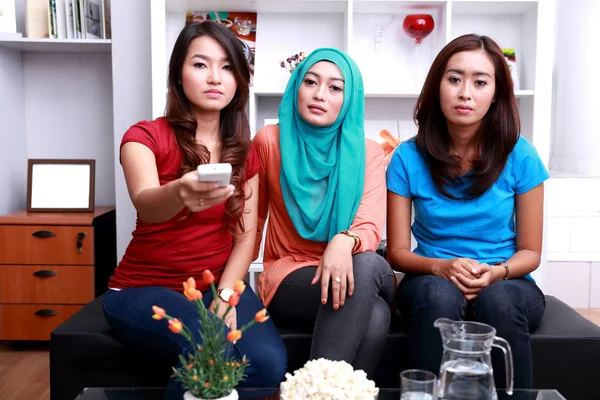Tre unga kvinnor med platt ansikte uttryck när du tittar på telev — Stockfoto