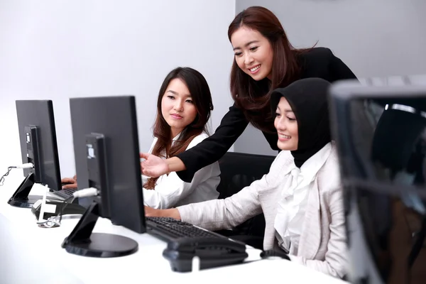 Drie vrouwelijke ondernemers kijken gelukkig wanneer ze over hun wor discussiëren — Stockfoto