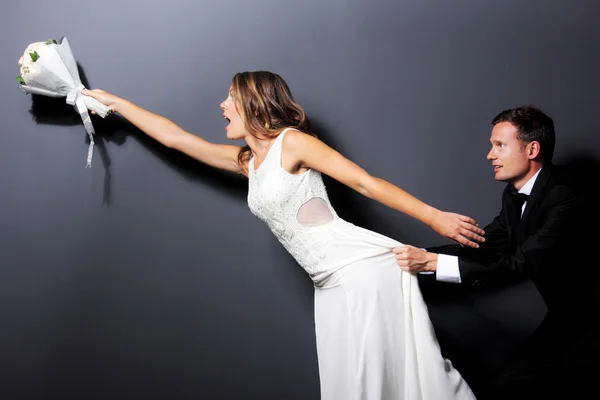 Bride and groom trying to catch a bouquet — Stock Photo, Image