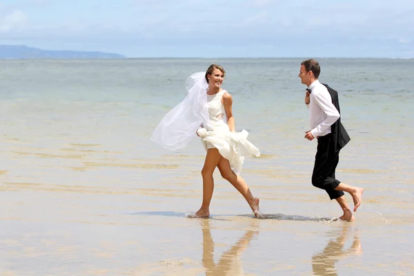 Jovem casal recém-casado brincando na praia — Fotografia de Stock