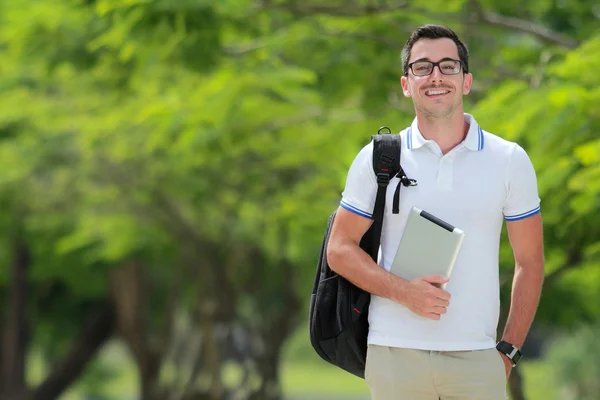 Étudiant souriant avec sac à dos tenant une tablette — Photo