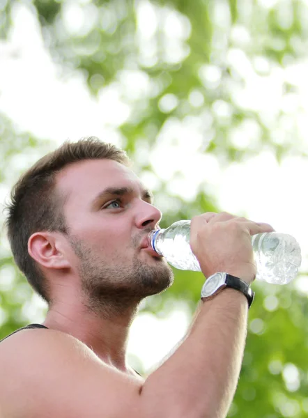 Coureur mâle boire de l'eau minérale à la pause après la course — Photo