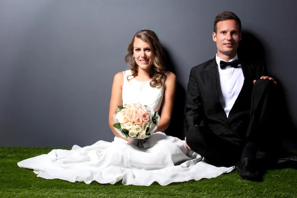 Young newlywed couple sitting on the  grass — Stock Photo, Image