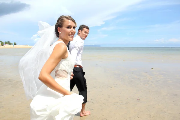 Coppia di sposi in esecuzione in spiaggia — Foto Stock