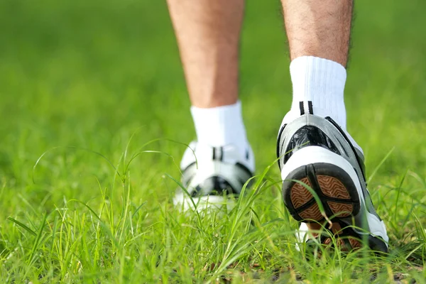 Menselijke voeten in loopschoenen aan stap op het gras — Stockfoto