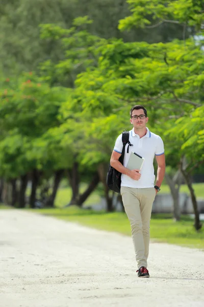 Knappe college student wandelen door in college park met backpac — Stockfoto