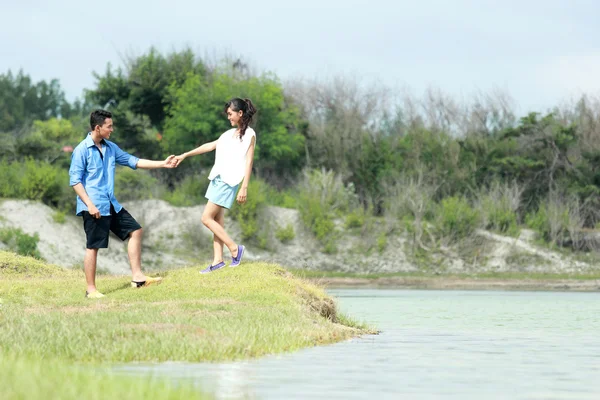 Романтическая пара, держащаяся за руки на берегу озера — стоковое фото