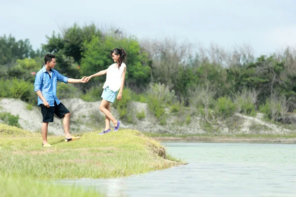 Pareja romántica cogida de la mano a orillas del lago — Foto de Stock