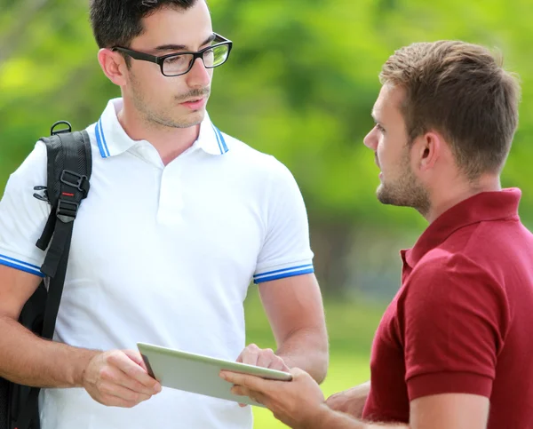 Uno studente universitario chiedendo di un incarico al suo amico utilizzando — Foto Stock