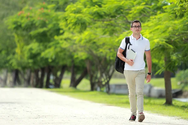 Handsome college student walking by at college park with backpac — Stock Photo, Image