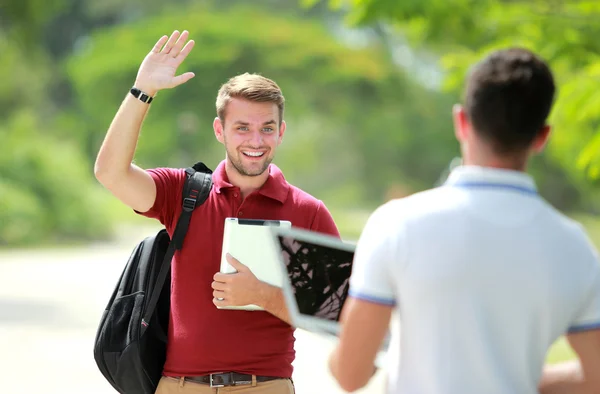 Üniversite öğrencisi karşılamak onun arkadaşı ve elini sallayarak — Stok fotoğraf