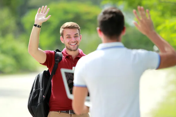 Estudiante universitario conocer a su amigo y saludar a su mano —  Fotos de Stock