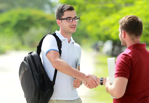 College student with glasses meet his friend at college park and — Stock Photo, Image