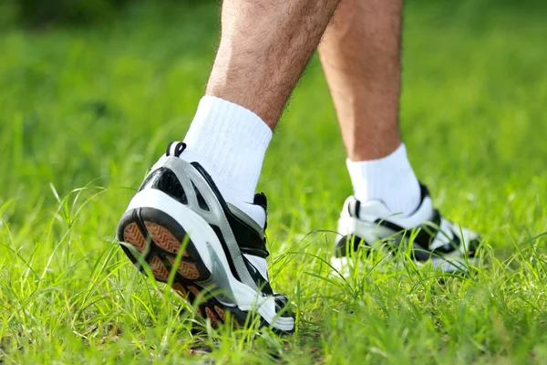 Menselijke voeten in loopschoenen aan stap op het gras — Stockfoto