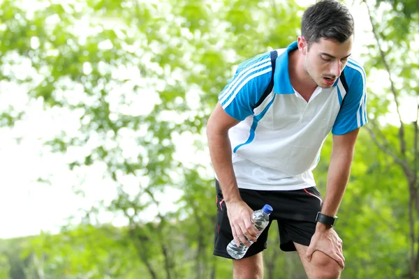 Sportieve mannelijke atleet nemen van een pauze na moe running — Stockfoto