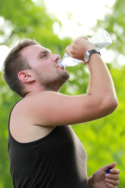Mężczyzna runner picie wody mineralnej w przerwie po uruchomieniu — Zdjęcie stockowe